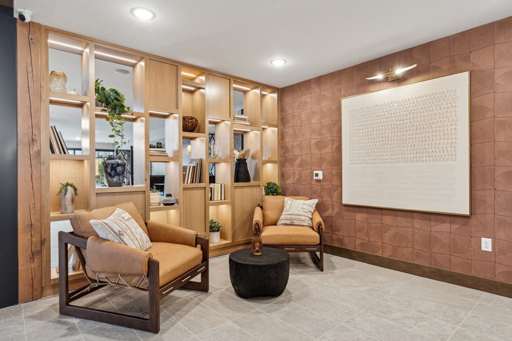 A living room with a brown sofa, a wooden chair, and a large painting on the wall.