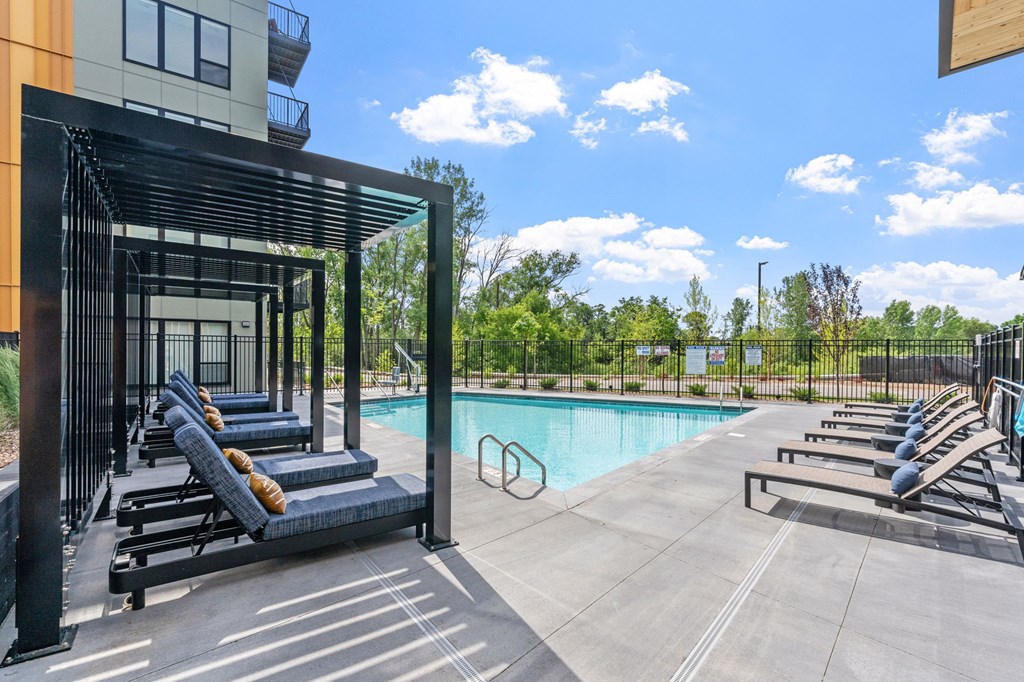 A pool area with sun loungers and a building in the background.