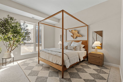 A bedroom with a canopy bed and a rug on the floor.