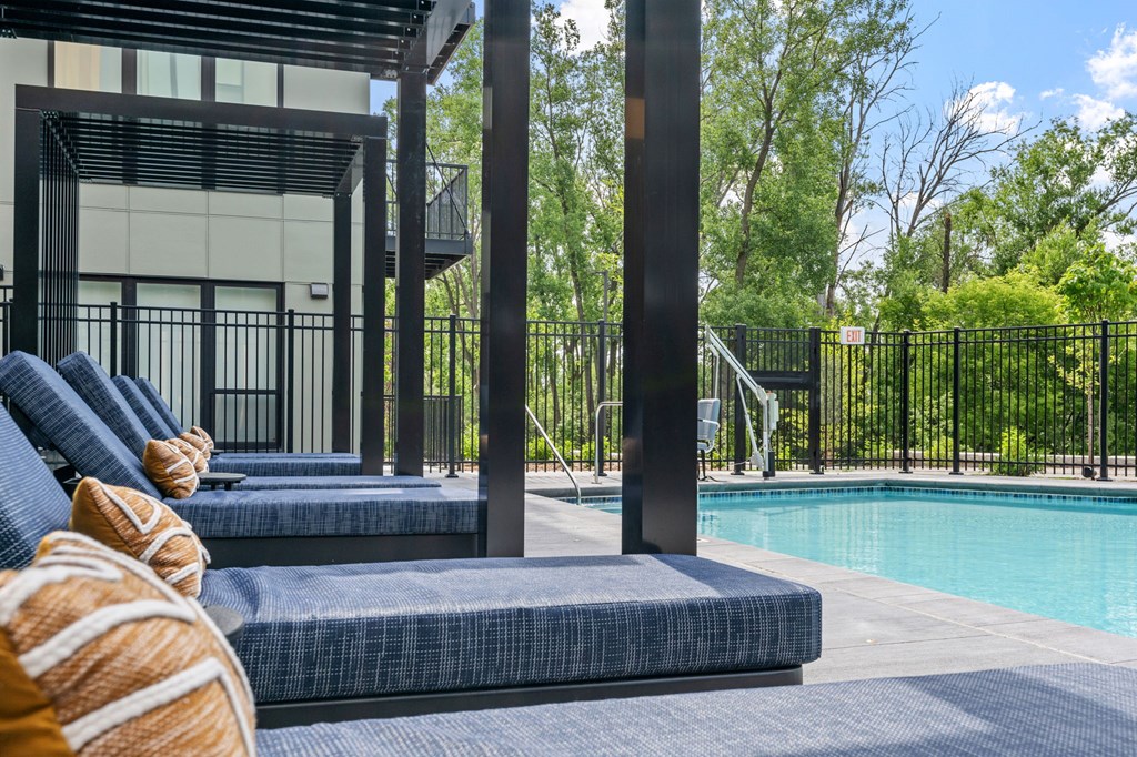 A poolside area with lounge chairs and a building in the background.