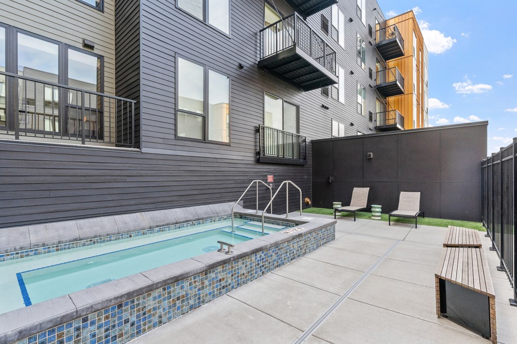 A small pool with a bench and a chair in front of a building.