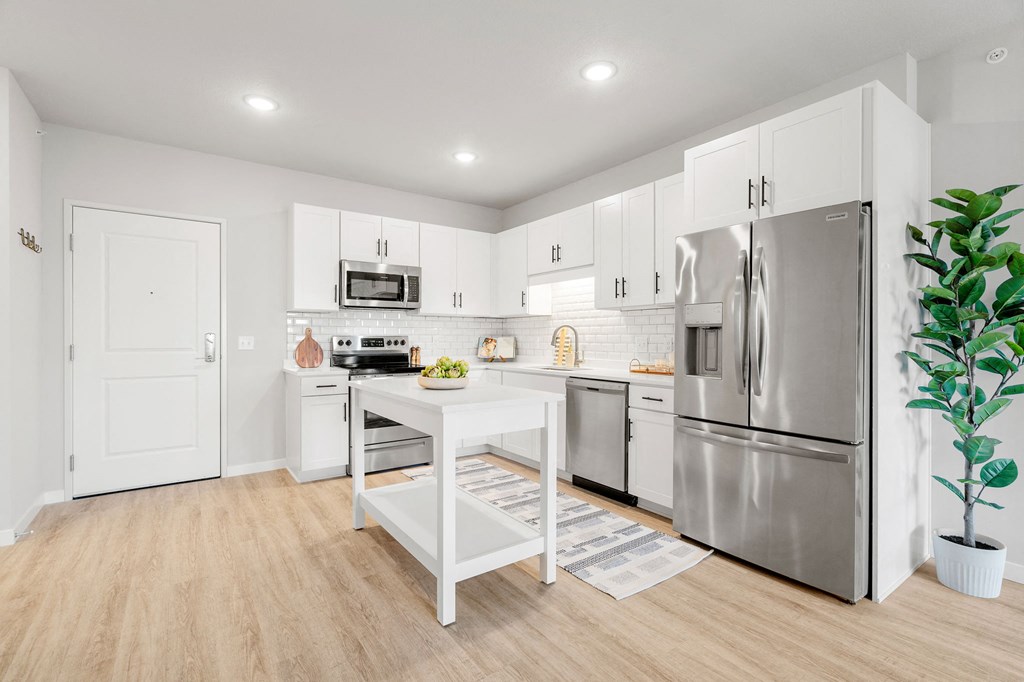 a white kitchen with stainless steel appliances and a white table