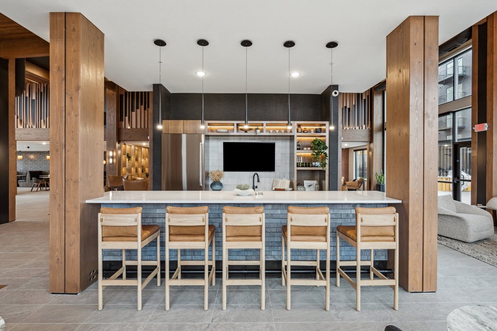A modern kitchen with a bar area and wooden chairs.