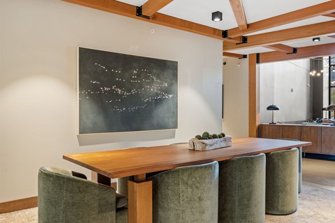 A dining room with a wooden table and green chairs.