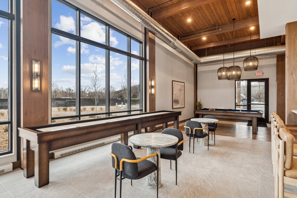 A room with a long table and chairs with a view of the outside.