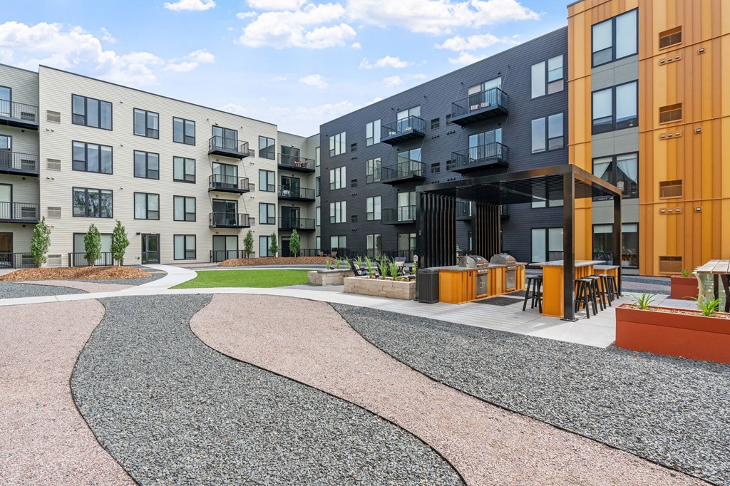 A modern apartment complex with a gravel courtyard in the foreground.