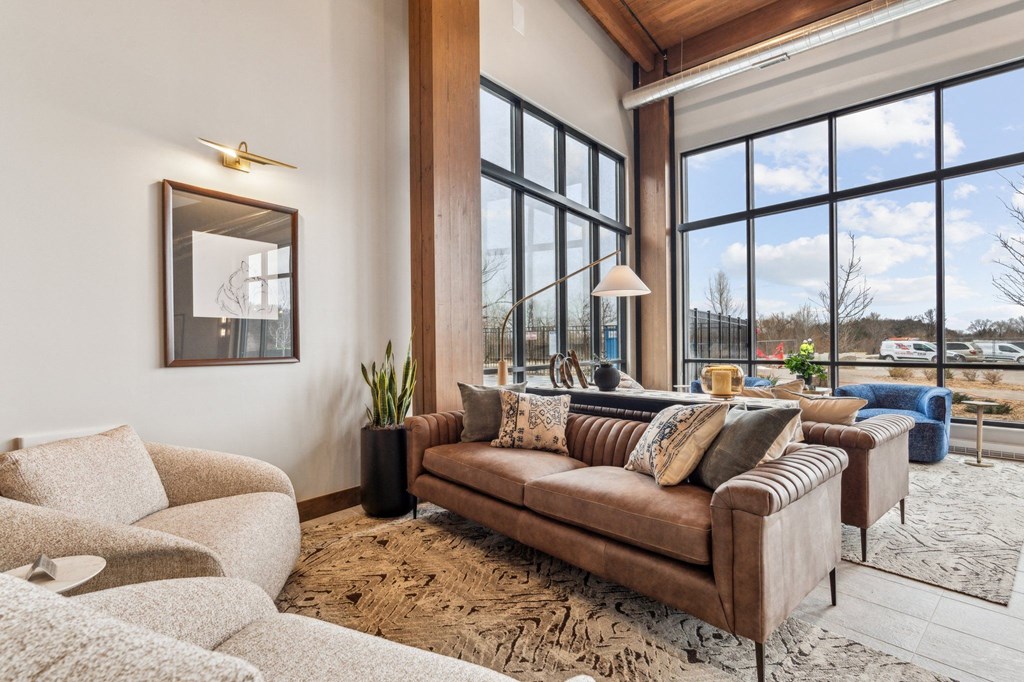 A living room with a brown couch and a large window.