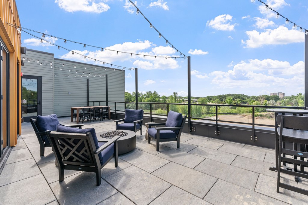 A patio with chairs and a table is set up on a balcony.