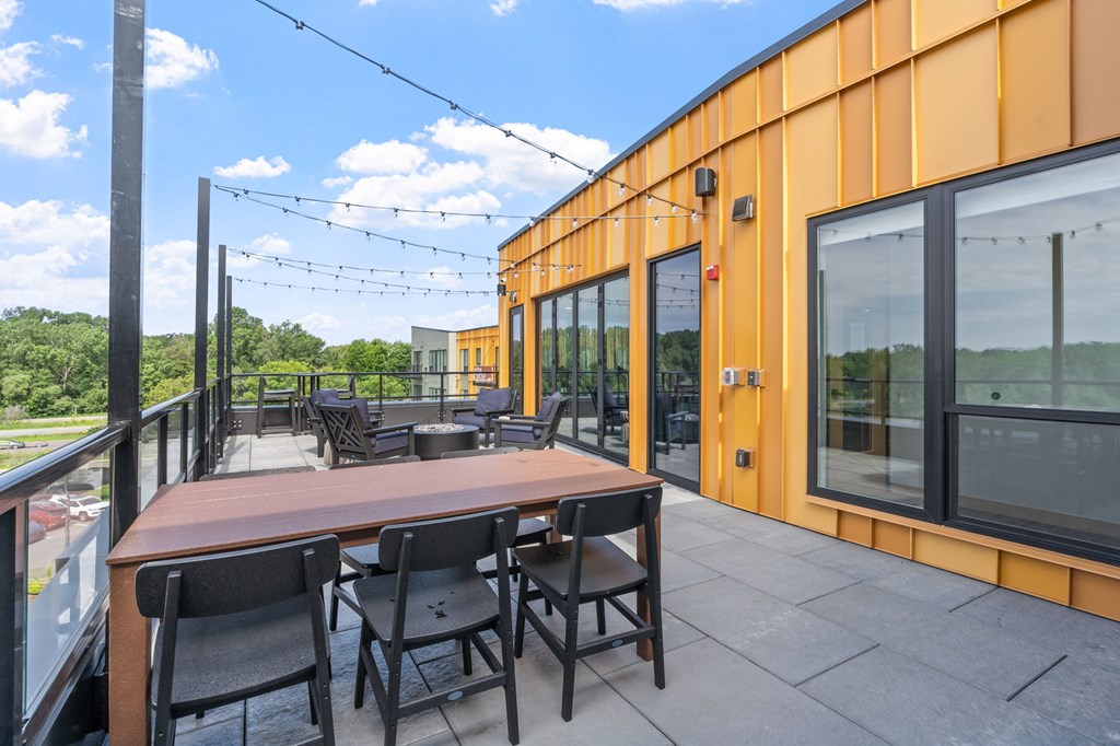 A patio with a table and chairs overlooking a green landscape.