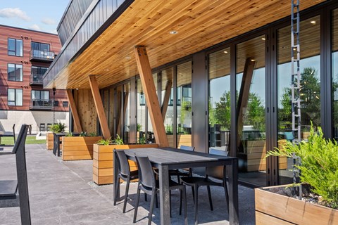 A modern outdoor dining area with a wooden table and chairs.