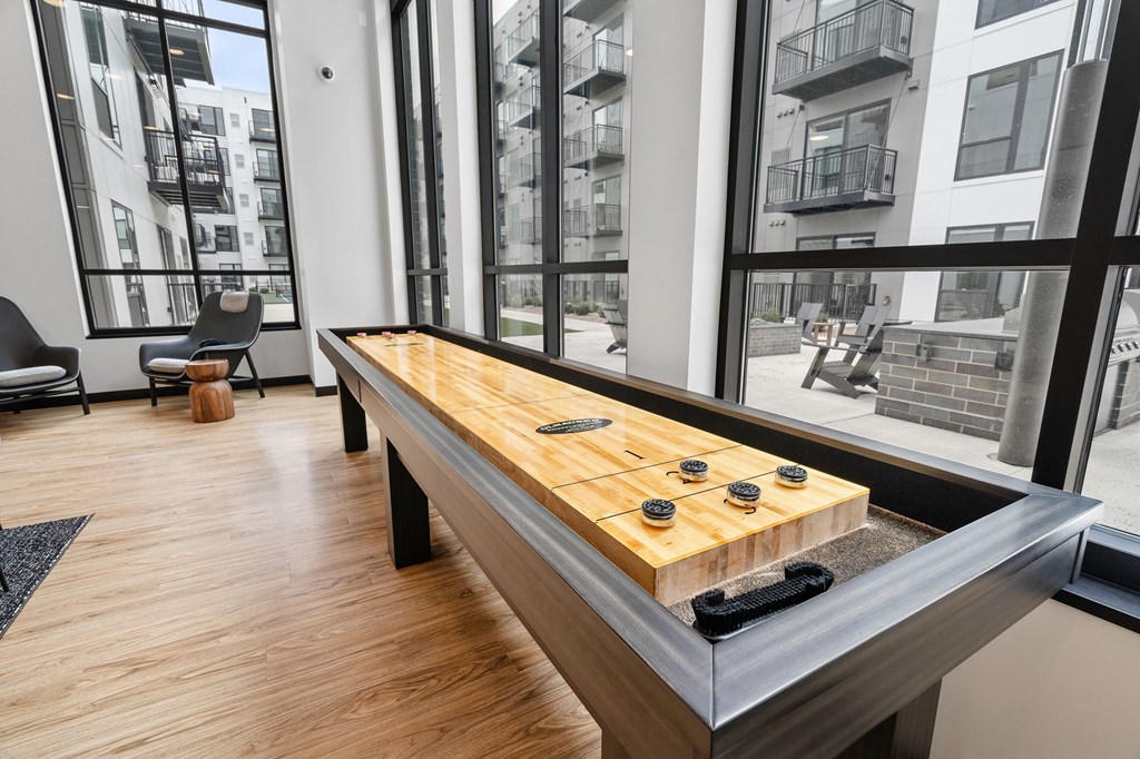 a shuffleboard table in a living room with large windows