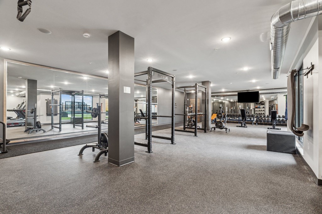 A gym with a variety of equipment including treadmills, weights, and exercise machines.