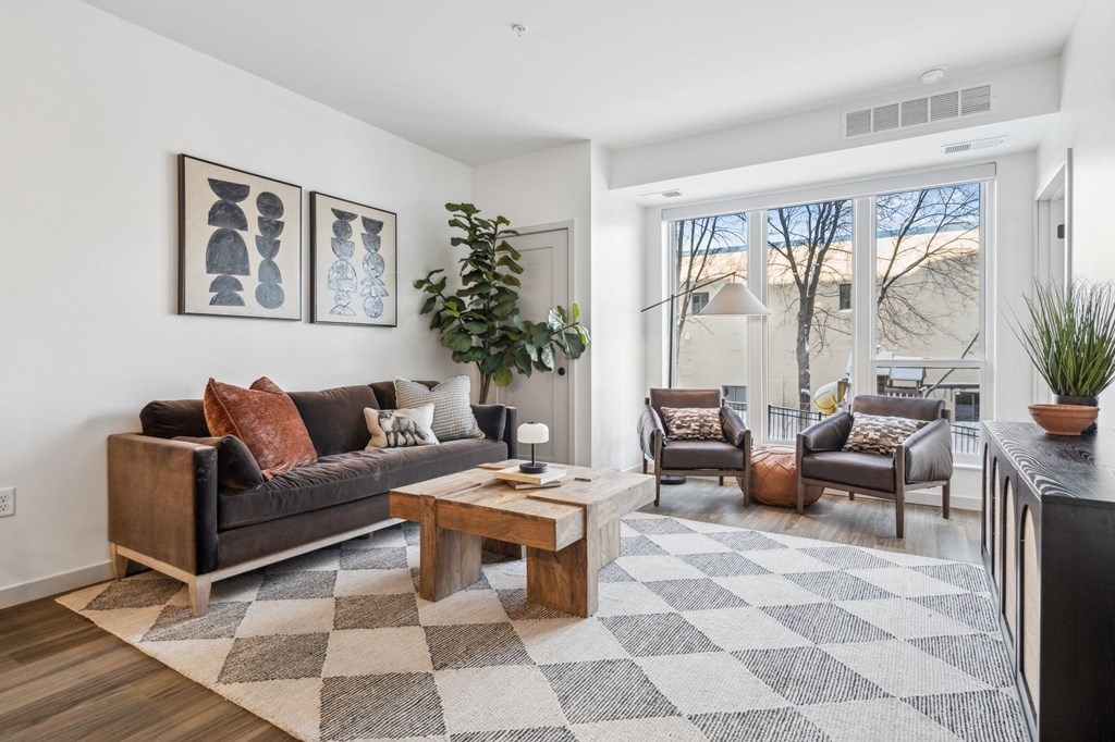 A living room with a black couch, a coffee table, and a rug.
