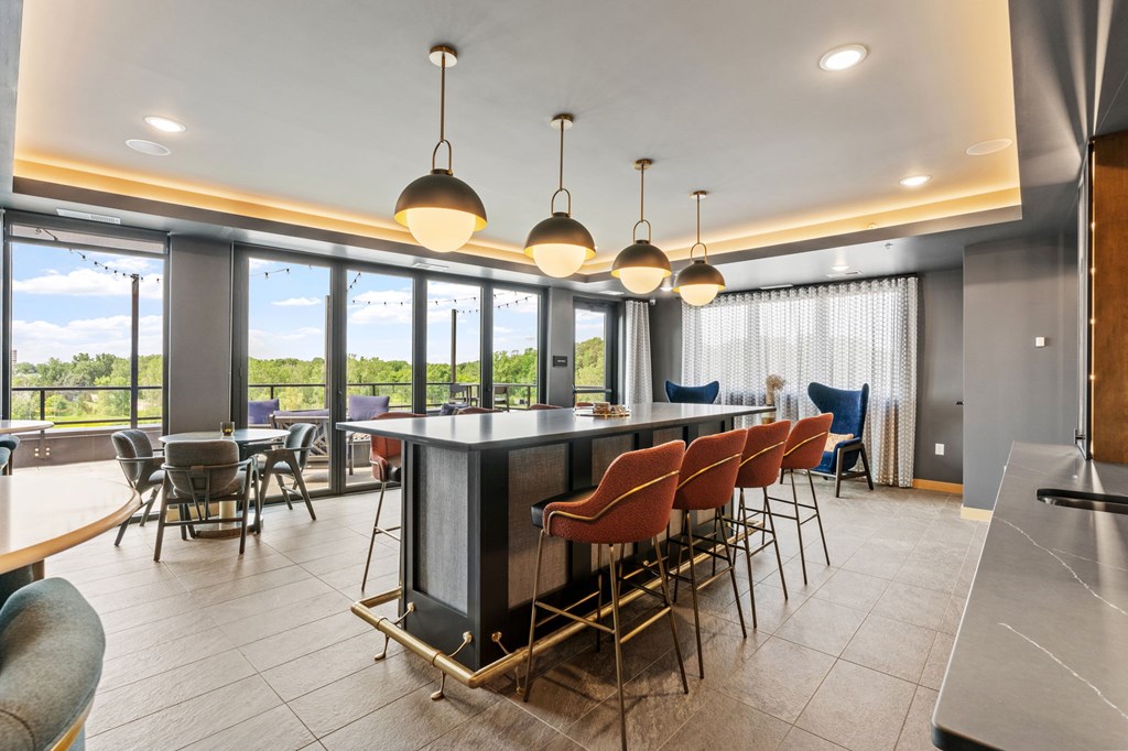 A modern kitchen with a bar area and chairs.