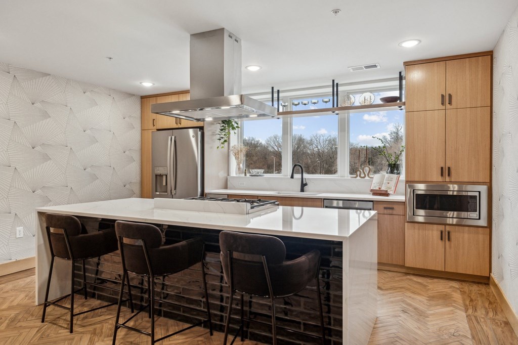 A modern kitchen with a large island and chairs.
