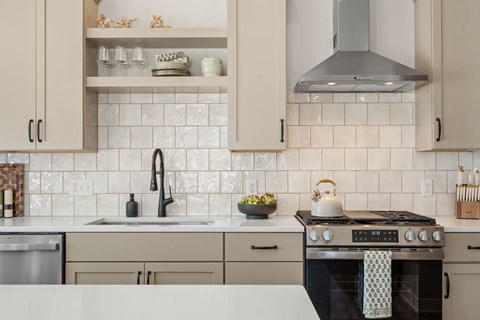 A kitchen with a black stove top oven and a white backsplash.