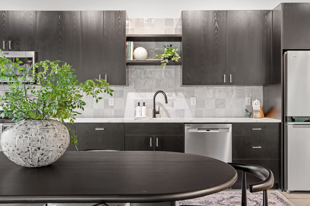 a kitchen with black cabinetry and a table with a potted plant