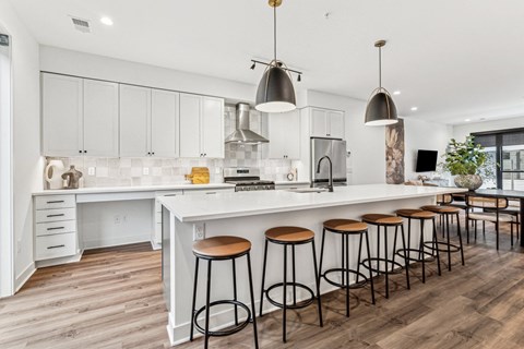 A kitchen with white cabinets and a white island with four stools.
