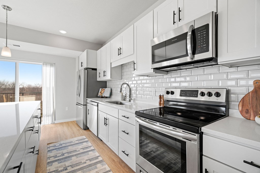a white kitchen with stainless steel appliances and a microwave