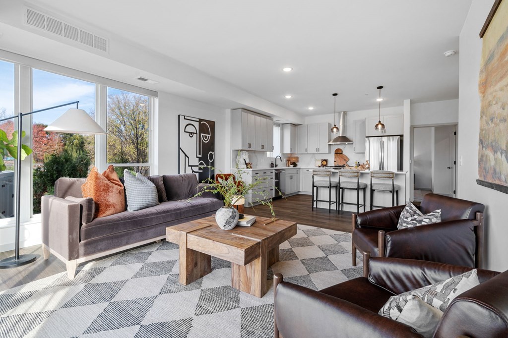 a living room with couches and a coffee table in front of a kitchen