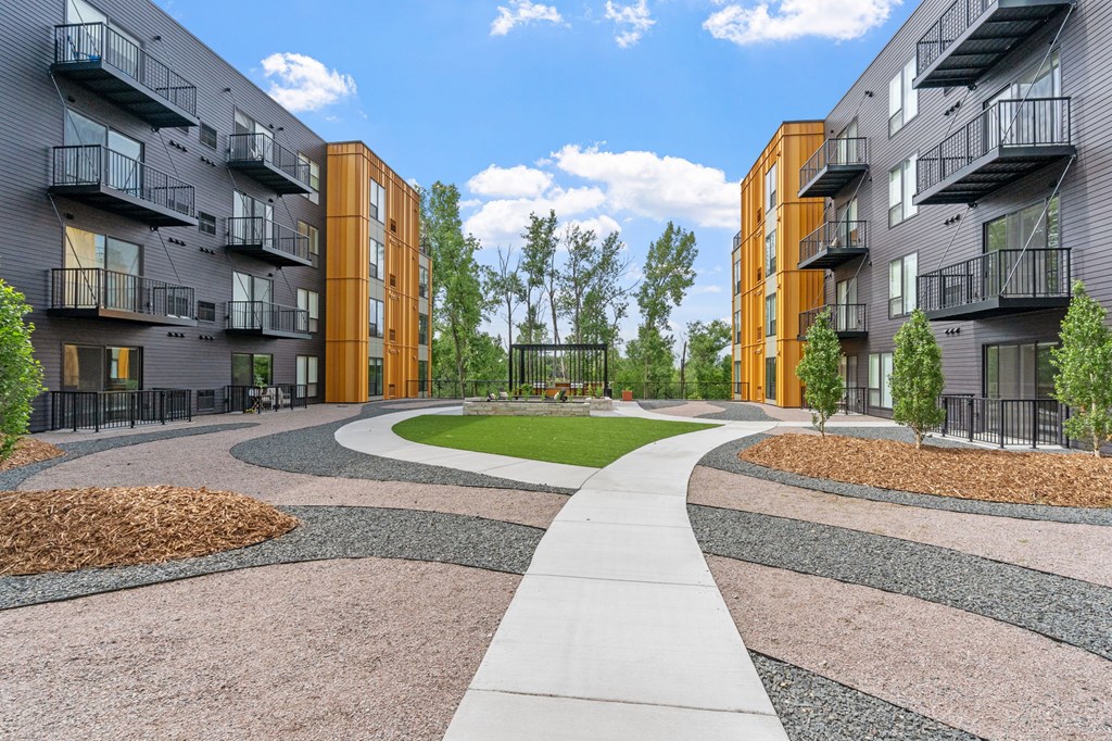 A modern apartment complex with a central walkway and landscaped gardens.
