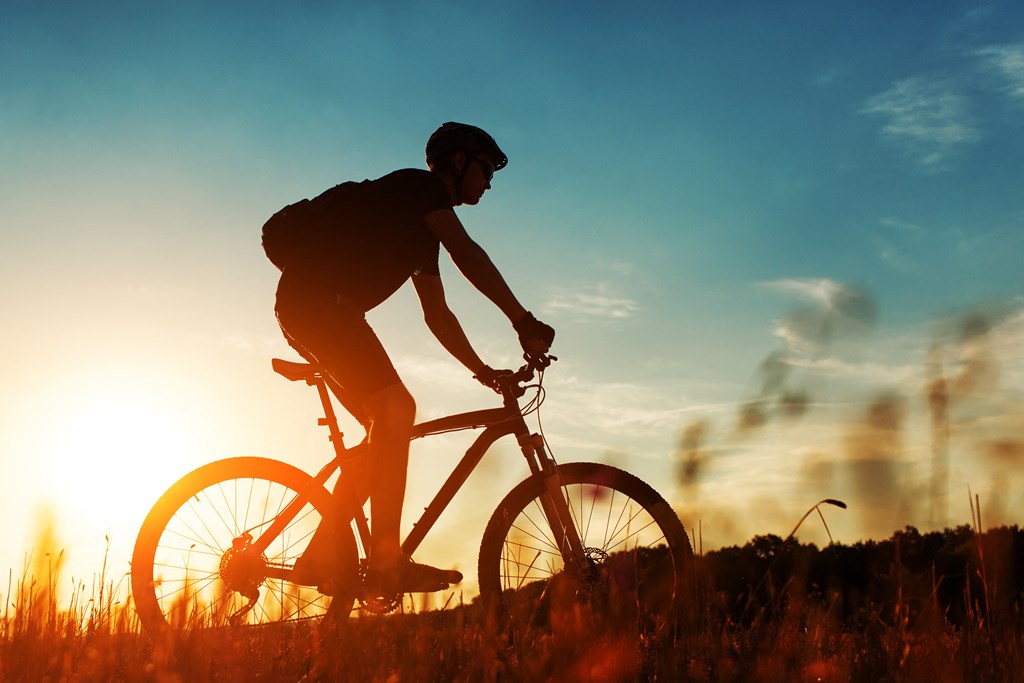 a man riding a bike on a hill at sunset