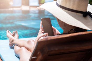 woman using a cell phone in a pool while wearing a hat