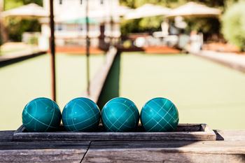 four blue balls on a wooden table by a swimming pool