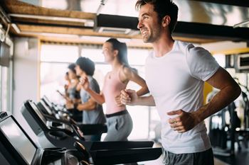 a group of people running on a treadmill in a gym