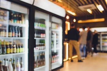 people standing in front of refrigerators in a supermarket
