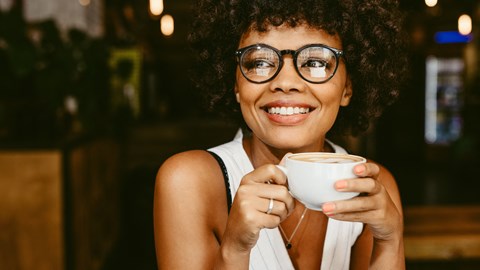 a woman with glasses holding a cup of coffee