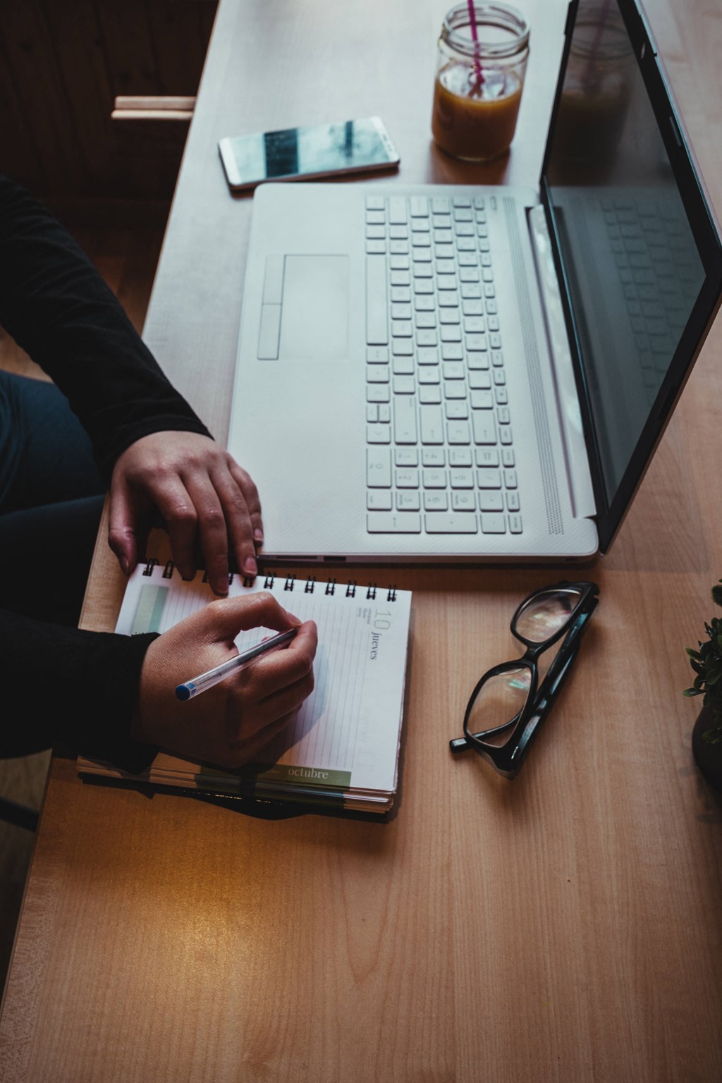 a person sitting at a desk with a laptop computer and a notebook