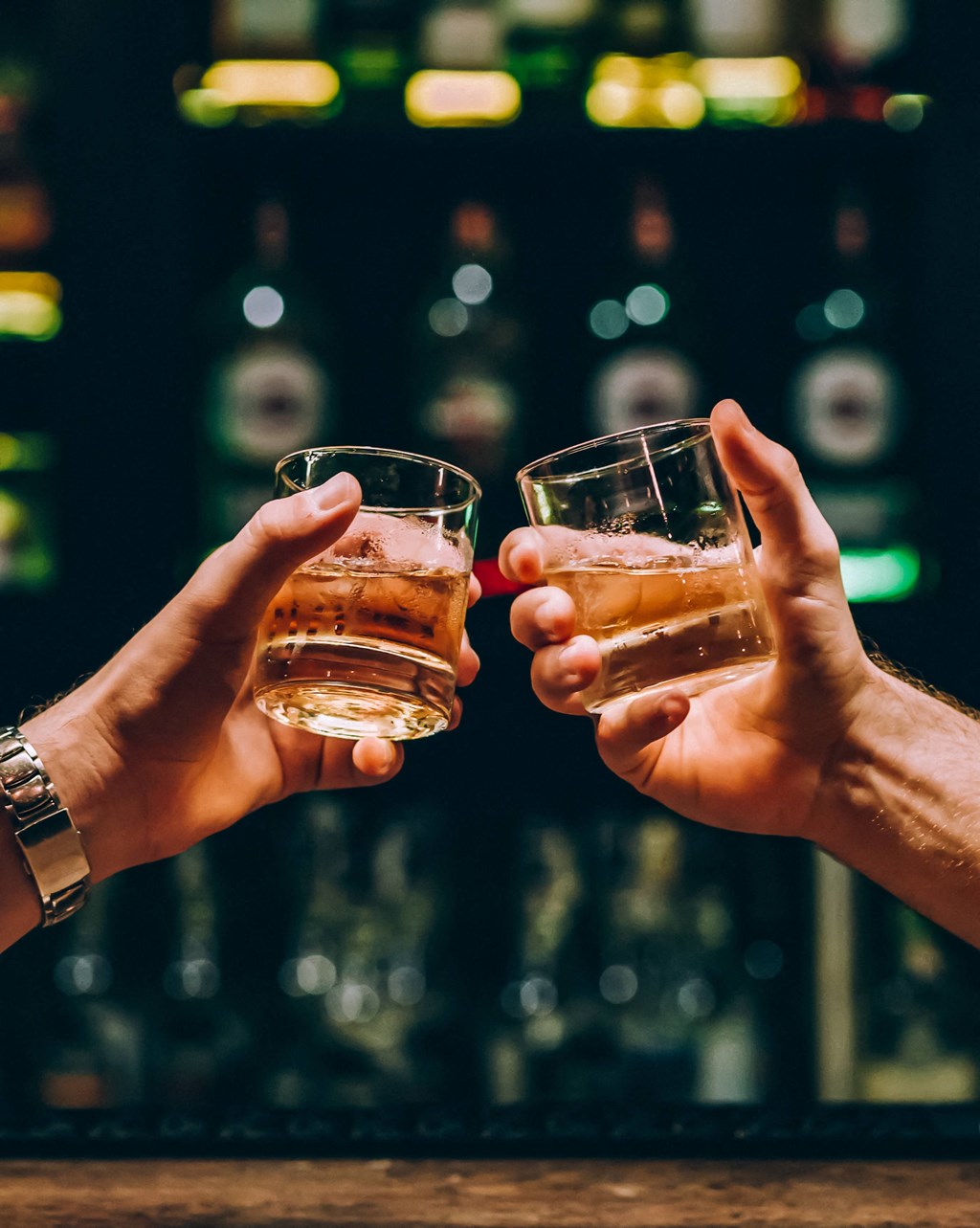 two people holding up two glasses of whiskey