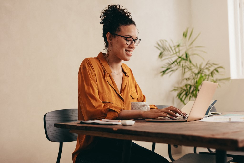 a woman sitting at a table using a laptop computer