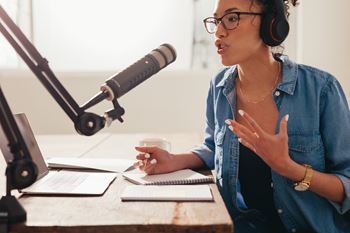 a woman sitting at a desk with a microphone and a laptop