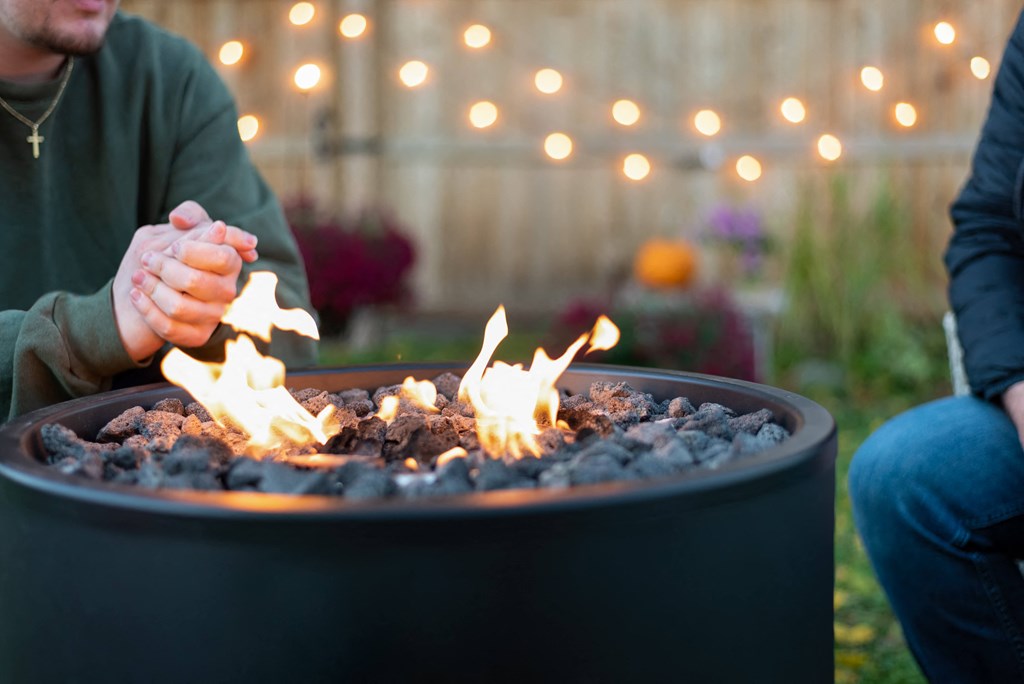 two people sitting around a fire pit burning coal