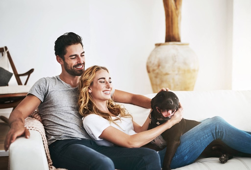 a man and woman sitting on a couch with a dog