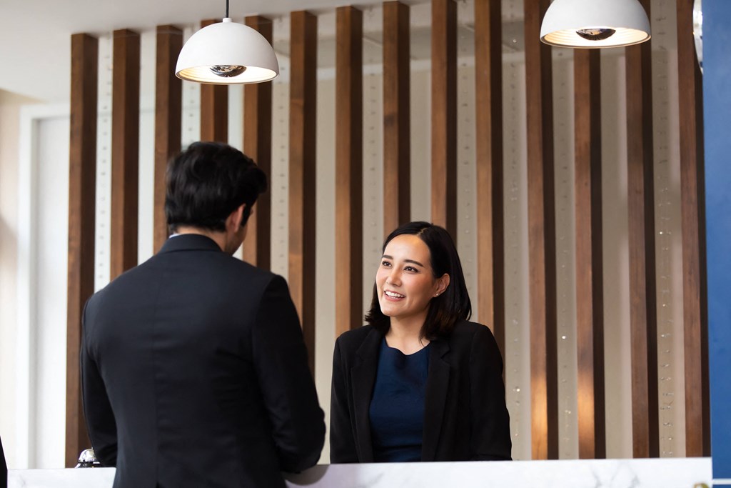 a woman smiling at a desk in front of a mirror