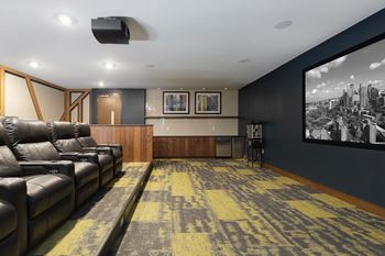 a living room with a large screen tv and leather couches