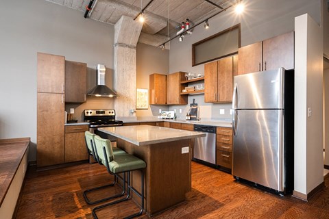 A kitchen with a stainless steel refrigerator and wooden floors.
