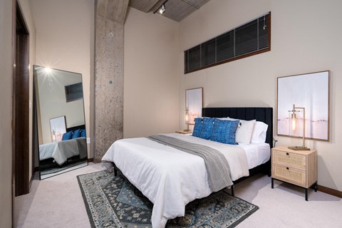 A bedroom with a large bed and a mirror on the wall.