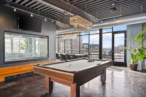 A pool table in a room with a view of the city.