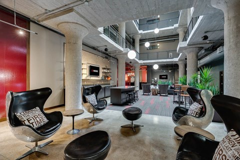 A modern living room with black chairs and a red wall.