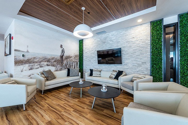 Spacious lounge seating social room with large screen TV at La Voile Broisbriand apartments in Broisbriand, Quebec