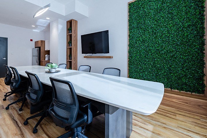 Conference room featuring large white central table and artificial living wall at La Voile Broisbriand apartments