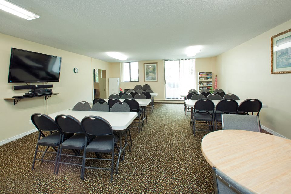 Wellington Park Towers social room with tables and chair and tv in St. Thomas, ON