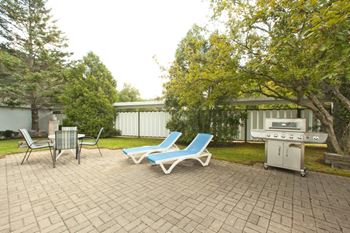 a patio with chairs and a grill and a table