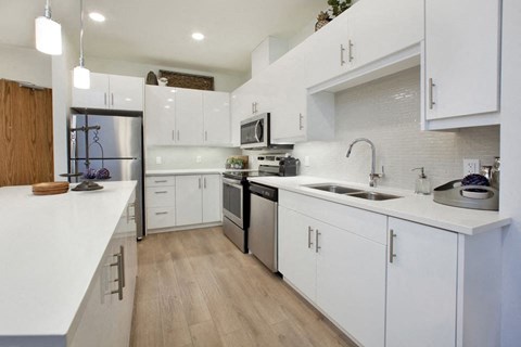a large white kitchen with a sink and a refrigerator