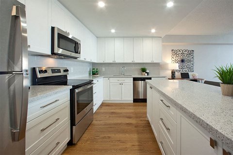 a large kitchen with white cabinets and stainless steel appliances