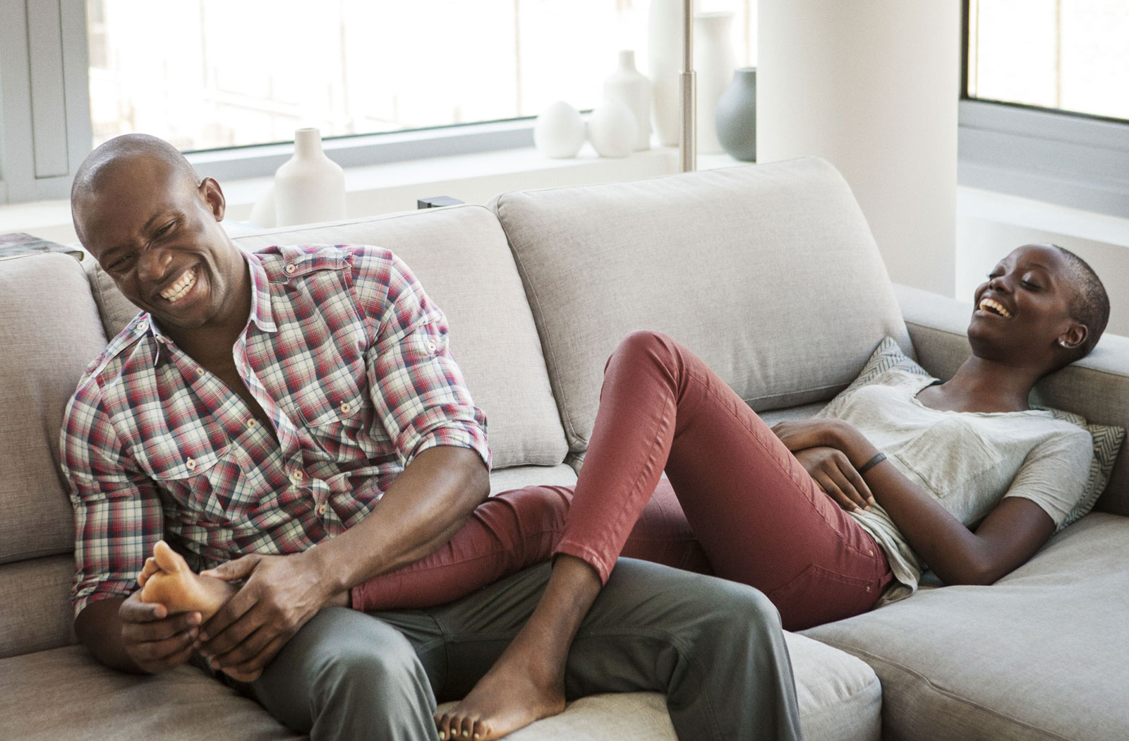 Professional adults, laughing on couch, enjoying Realstar’s apartment unit
